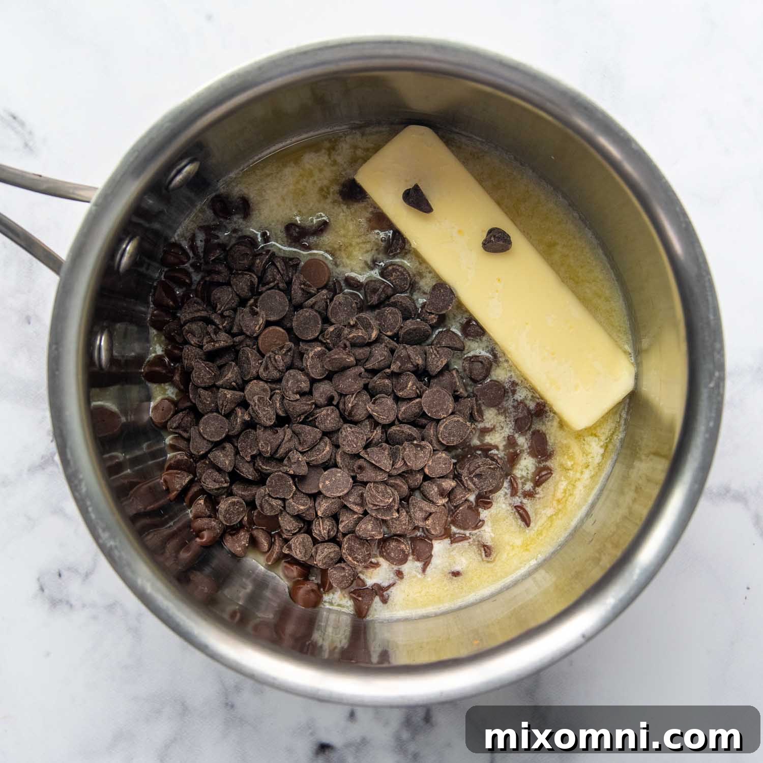 Butter and semisweet chocolate chips melting together in a saucepan, forming a rich, smooth base for the brownies.