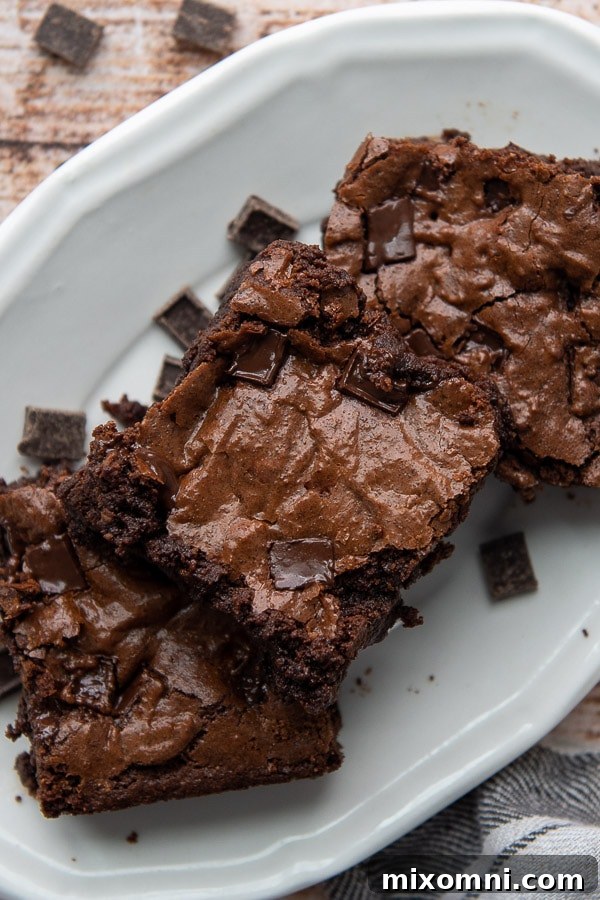 Overhead shot of three perfectly cut, fudgy almond flour brownies on a white plate, ready to be enjoyed.