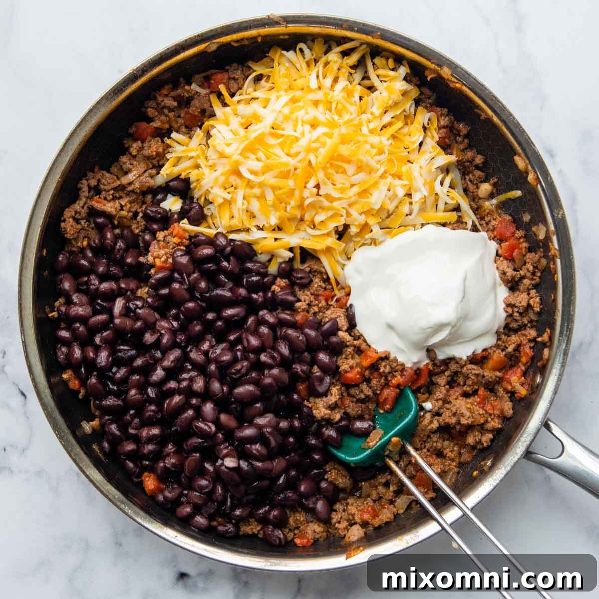 Black beans, shredded cheese, and sour cream stirred into the seasoned beef and tomato mixture.