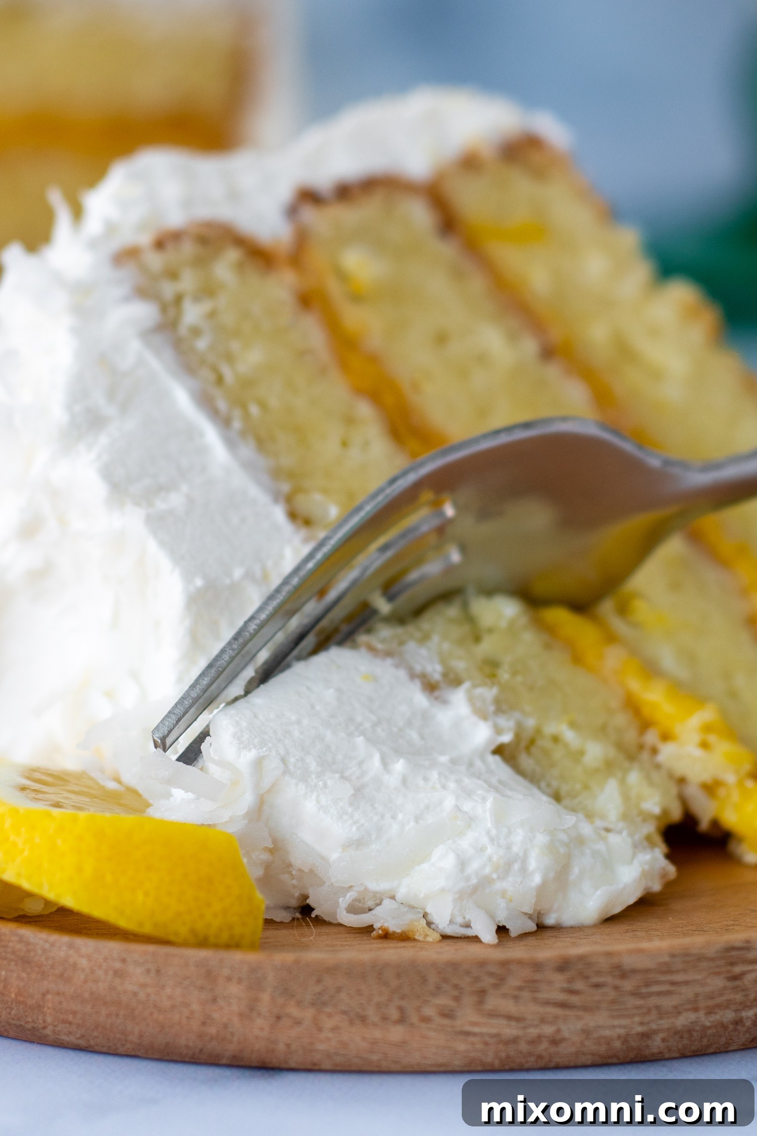 A fork entering a slice of gluten-free coconut lemon cake resting on its side, showcasing the layers and fluffy texture.