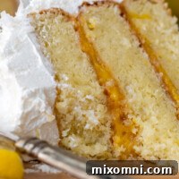 Close up of a bitten into slice of gluten-free coconut lemon cake on a wooden plate.
