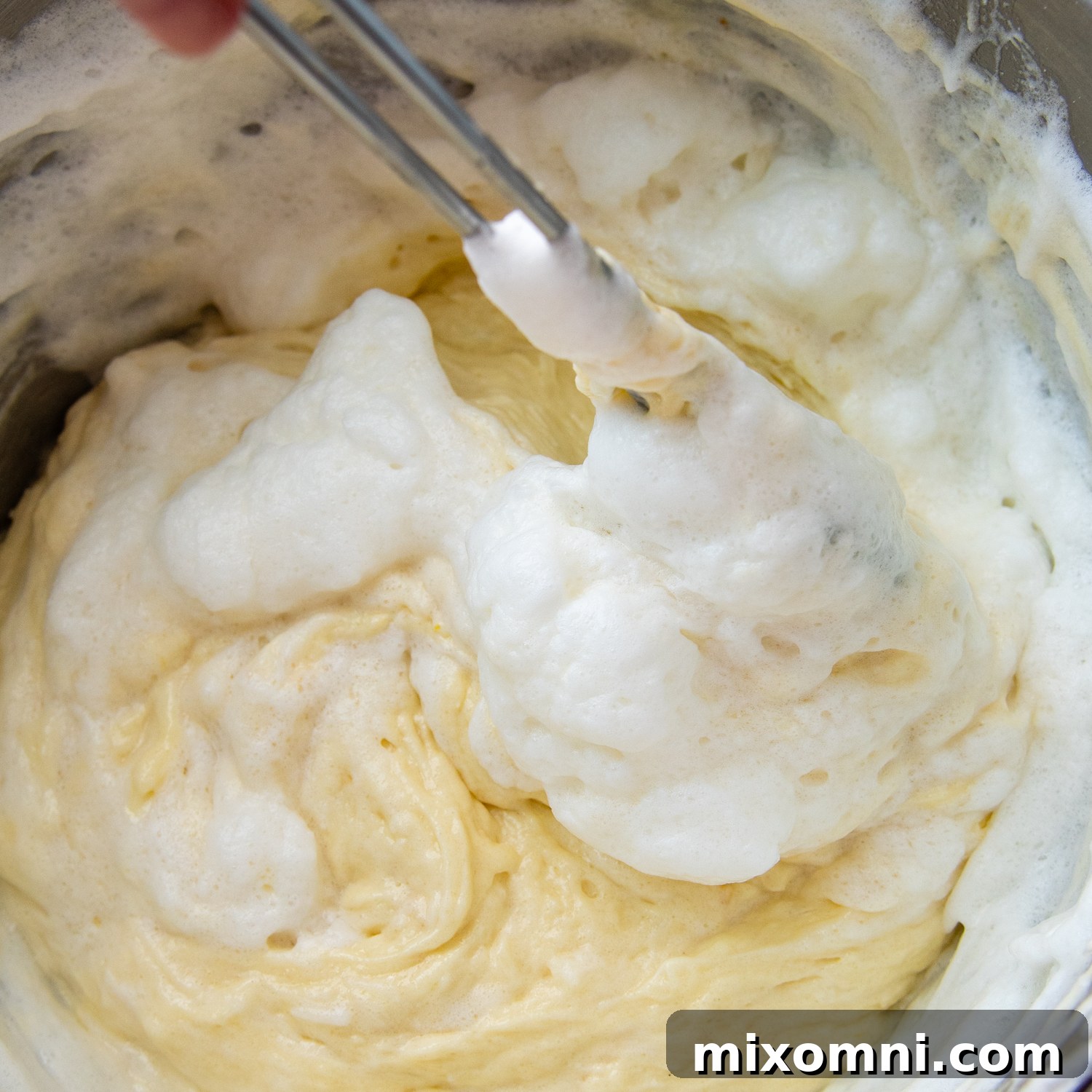 Light and airy egg whites being carefully folded into the cake batter, ensuring a fluffy texture.