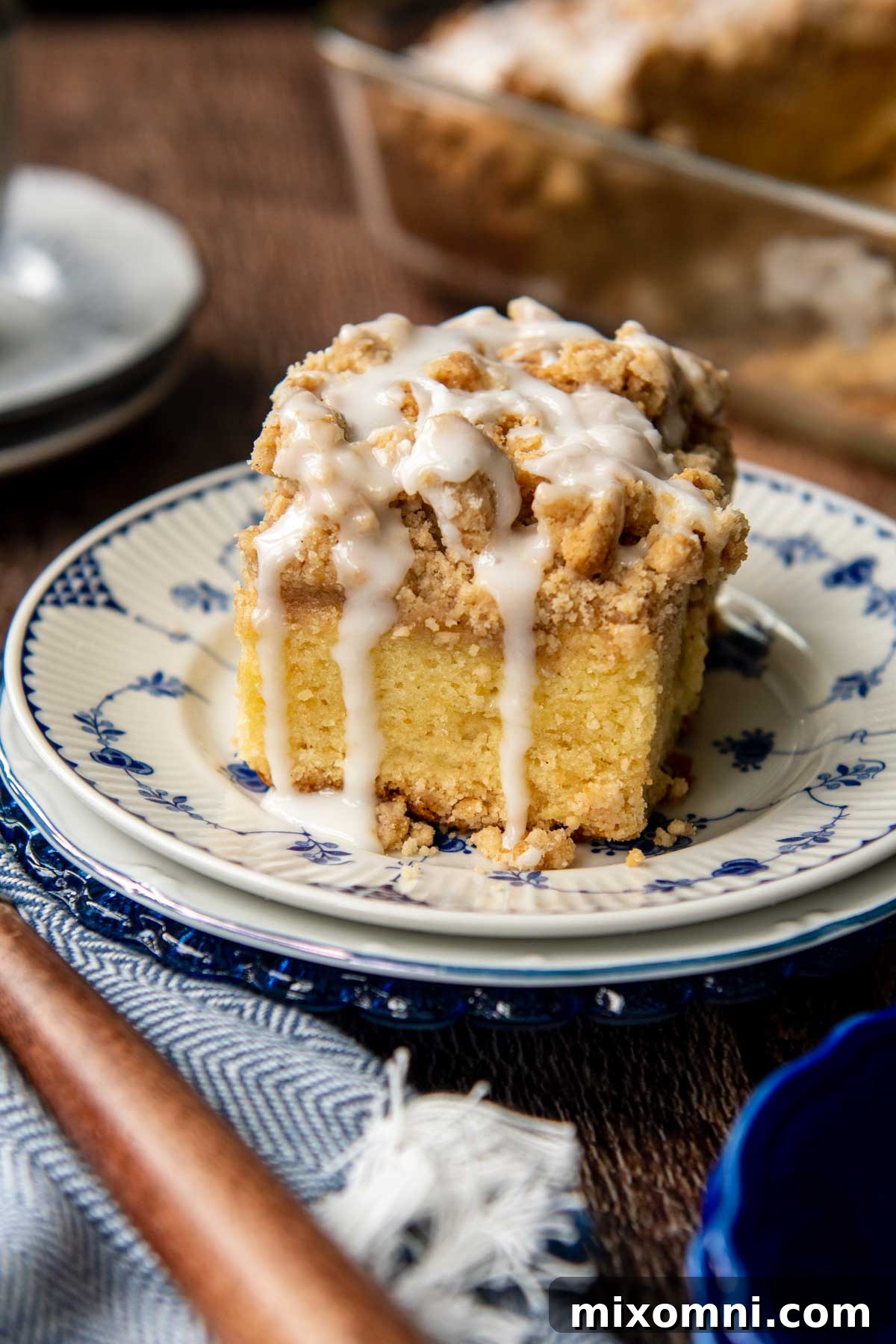 A delectable slice of moist gluten-free coffee cake, generously topped with cinnamon streusel and a vanilla glaze that drizzles down its sides.