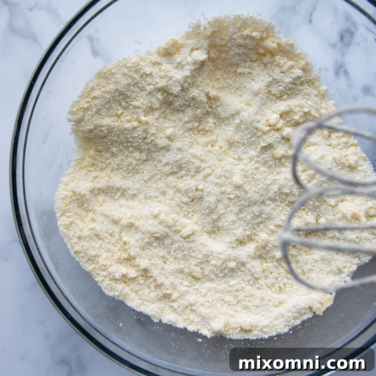 A mixer incorporates softened butter into dry ingredients for gluten-free coffee cake.