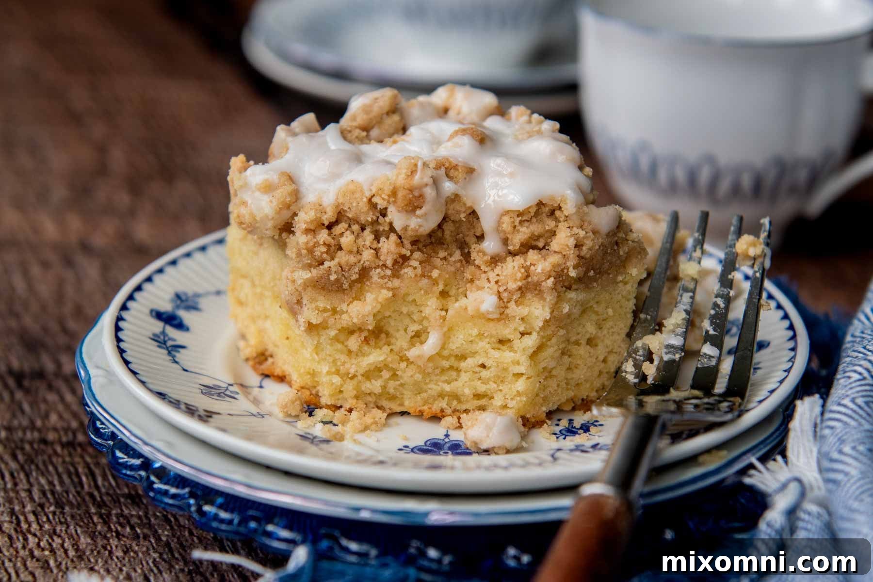 A delectable slice of coffee cake with a bite taken out, resting on a charming blue plate, showcasing its moist interior and generous streusel topping.