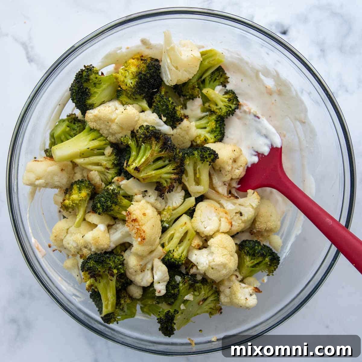 Tender broccoli and cauliflower florets generously coated in a rich, creamy cheese sauce, ready for baking.