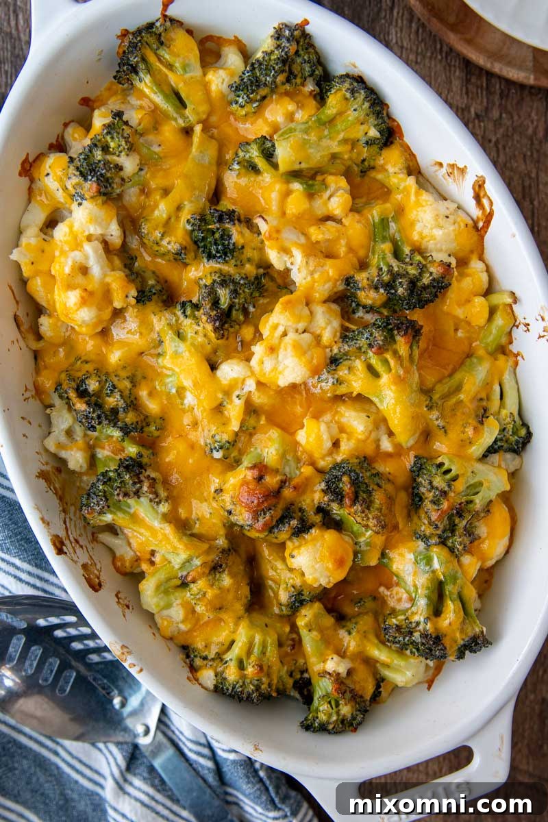 Overhead shot of a beautifully baked vegetable casserole in a white oval dish, rich with melted cheese.