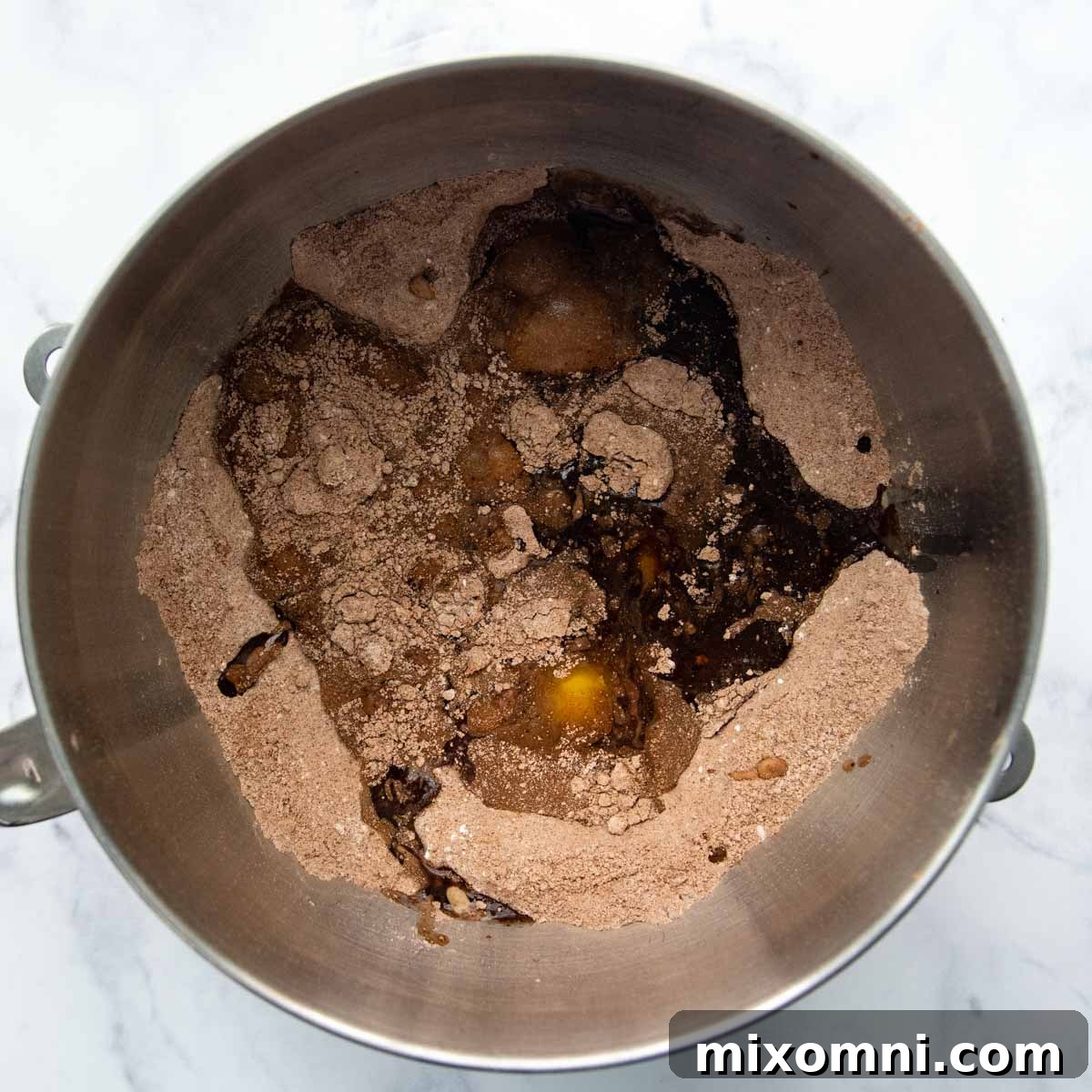 Adding eggs, milk, oil, and vanilla to the dry ingredients for the gluten-free chocolate cake batter.