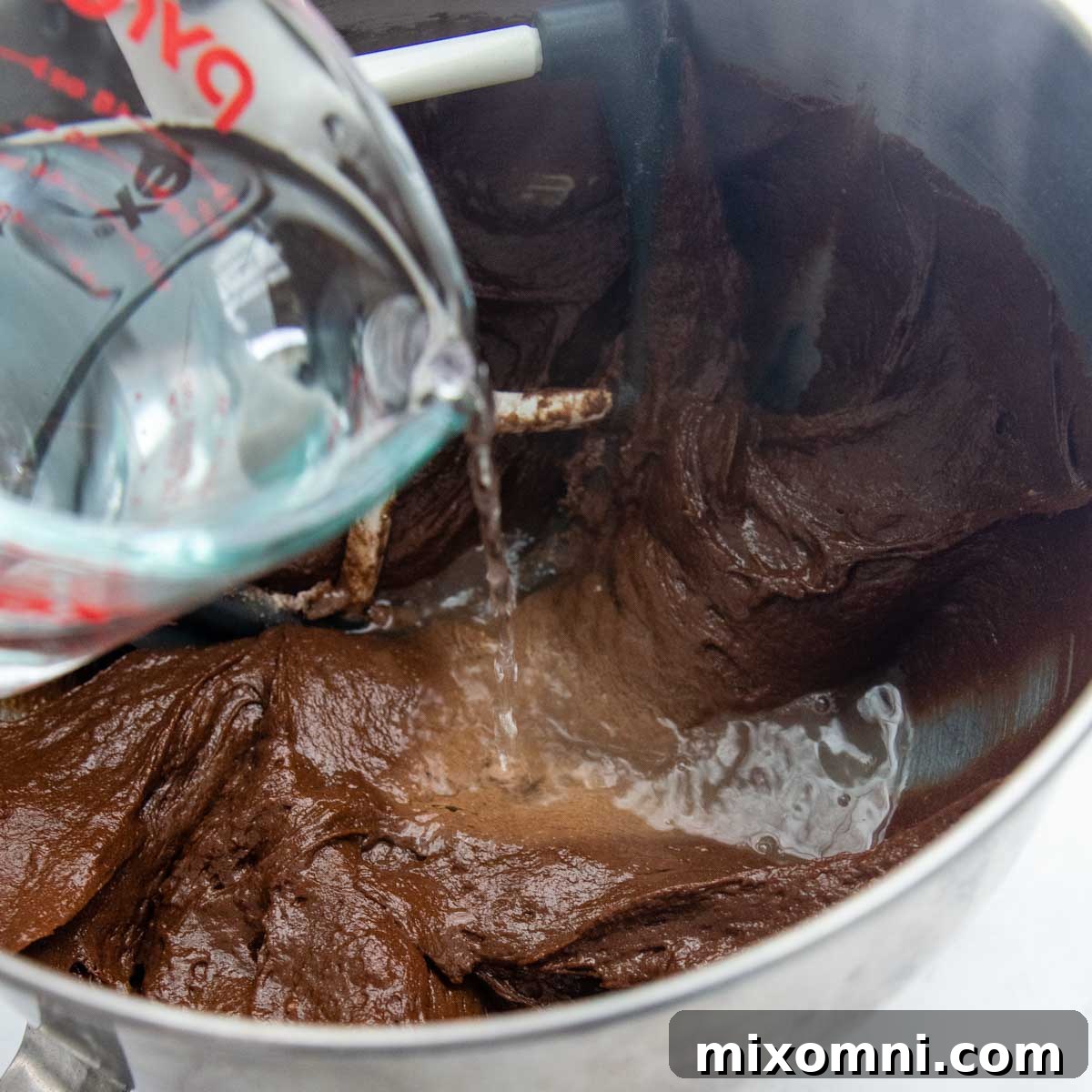 Pouring hot boiling water into the chocolate cake batter.
