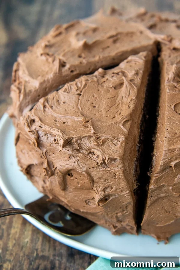 Decadent chocolate buttercream cake with a large slice ready to be enjoyed, highlighting the fluffy texture of the frosting.