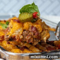A spatula lifting bacon cheeseburger casserole from a baking dish