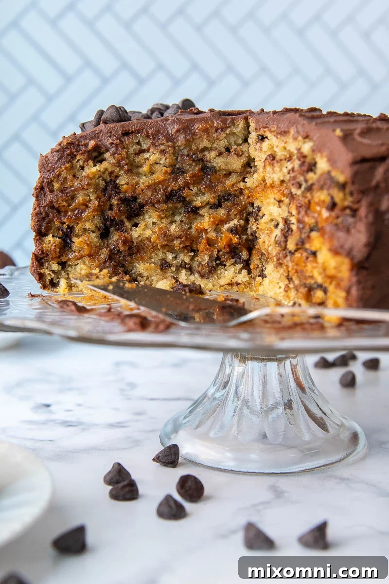 A sliced oatmeal layer cake, revealing its caramel filling and whipped ganache frosting, presented on a cake platter.
