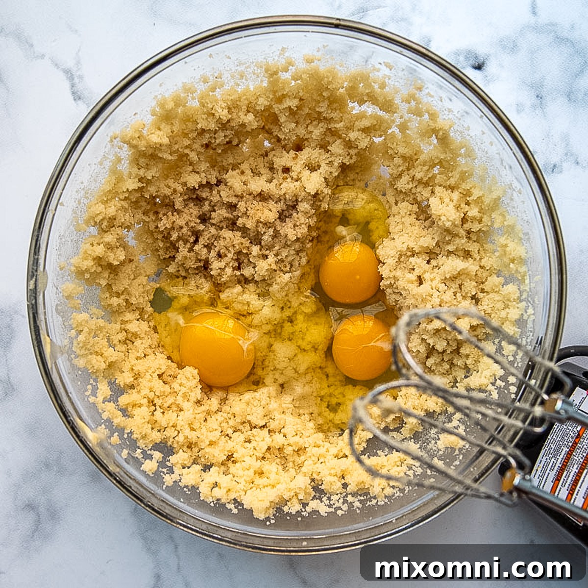 Cake batter being mixed with eggs, showcasing the creaming process.