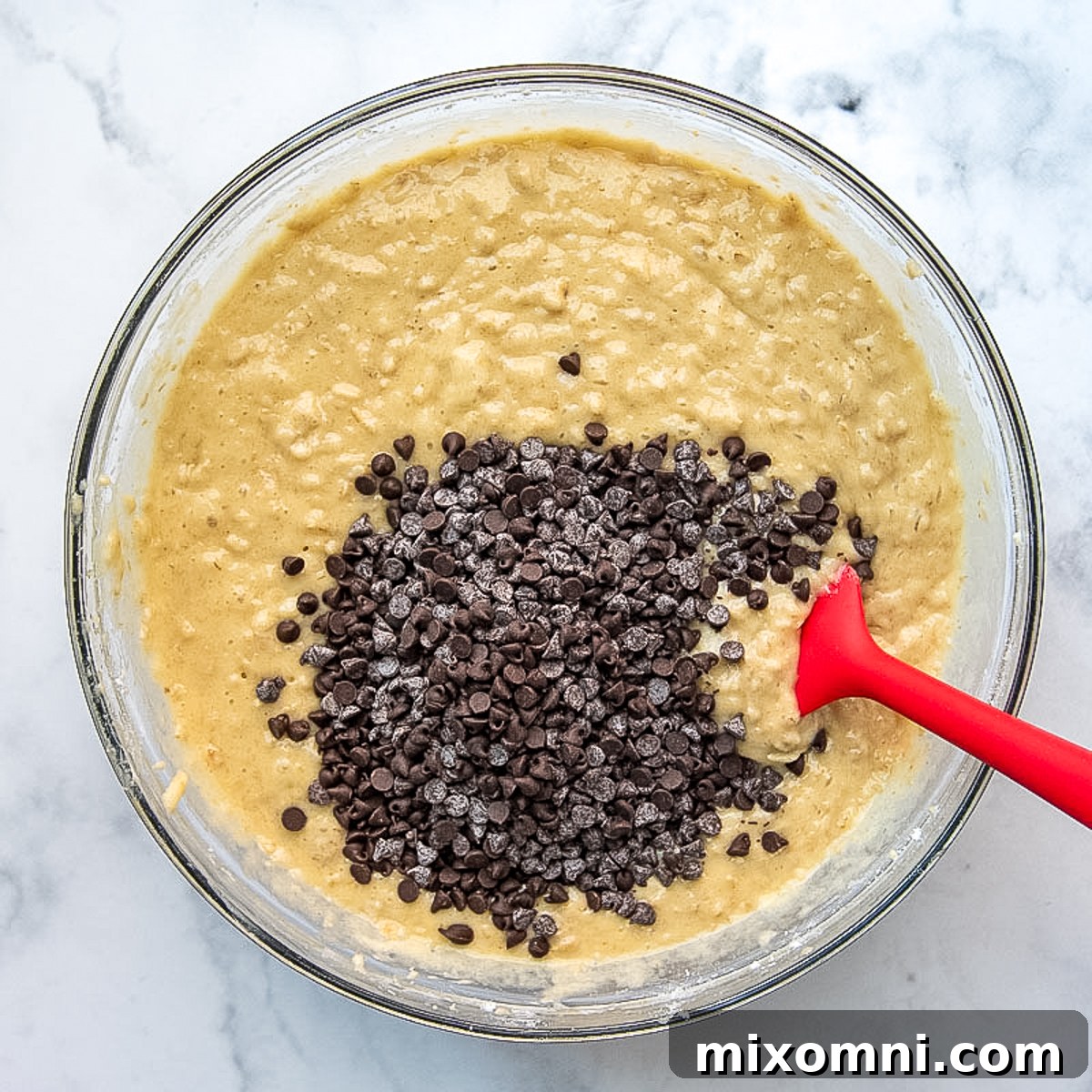 Mini chocolate chips being stirred into the cake batter, a final step before baking.