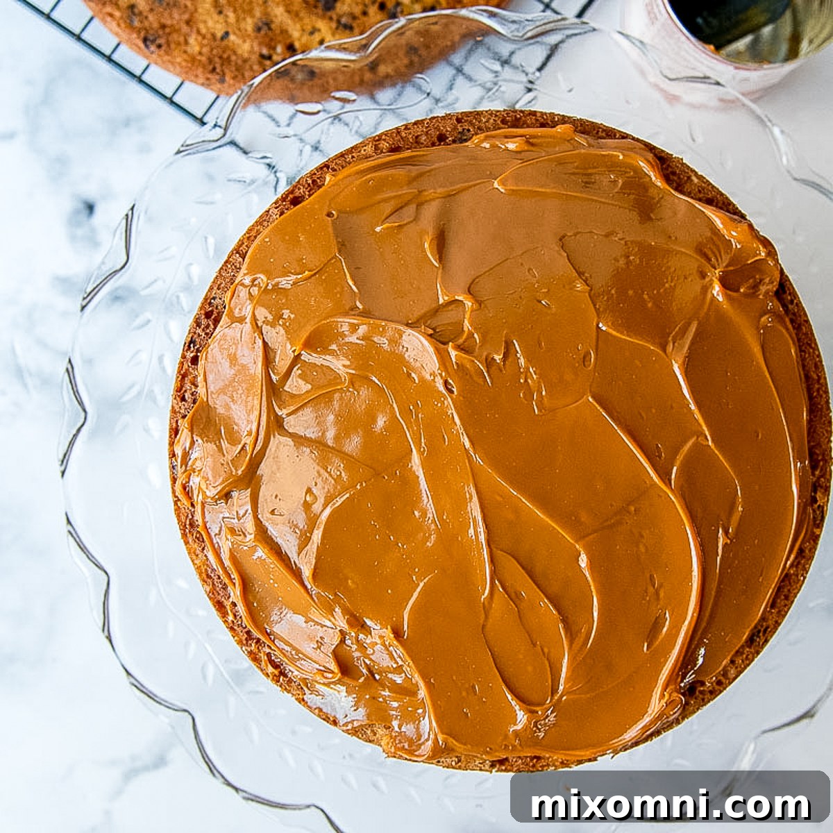 Dulce de leche caramel being smoothly spread onto a cake layer during assembly.