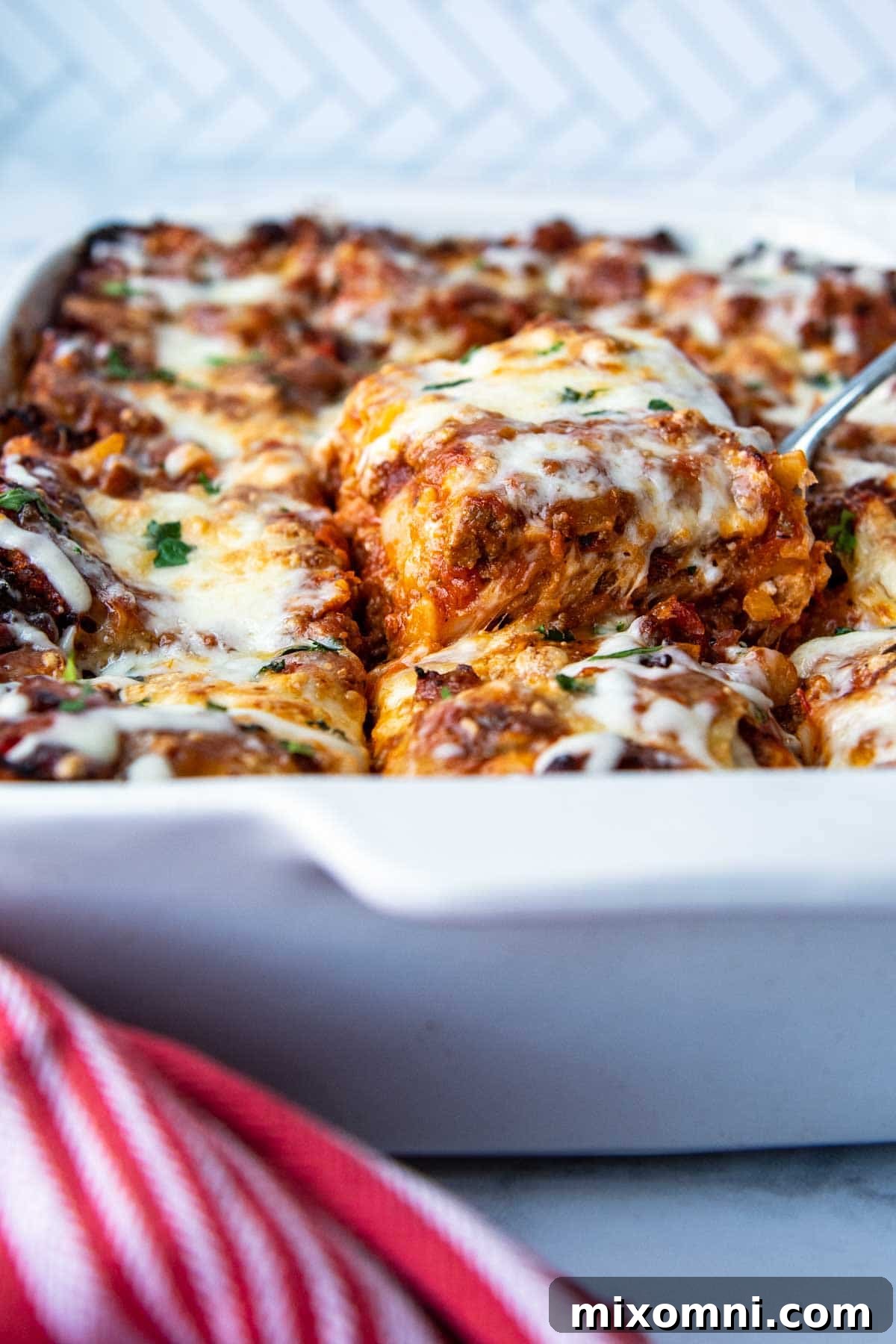 a slice of gluten-free lasagna being lifted from a white baking dish