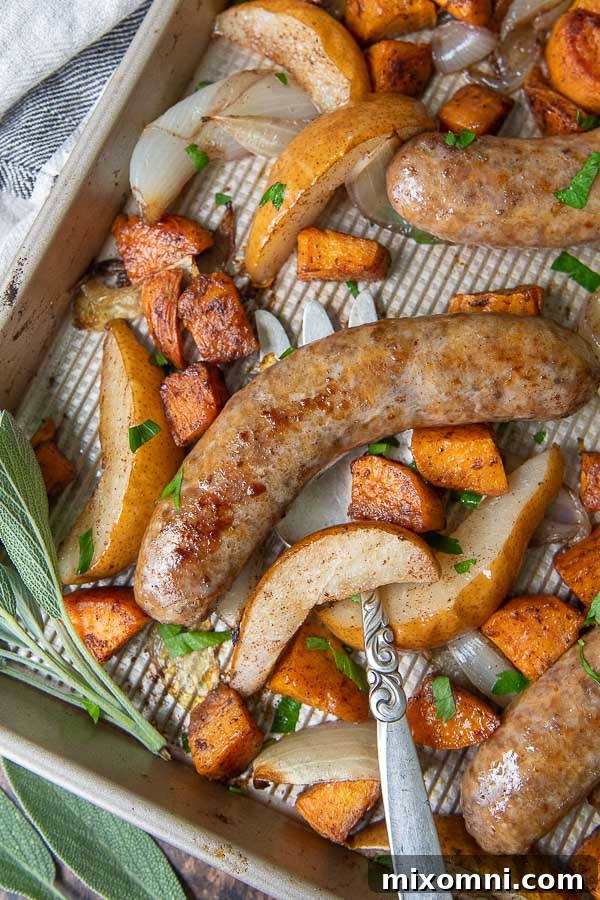 a close up overhead shot of baked italian sausage on a baking sheet with a large serving fork underneath