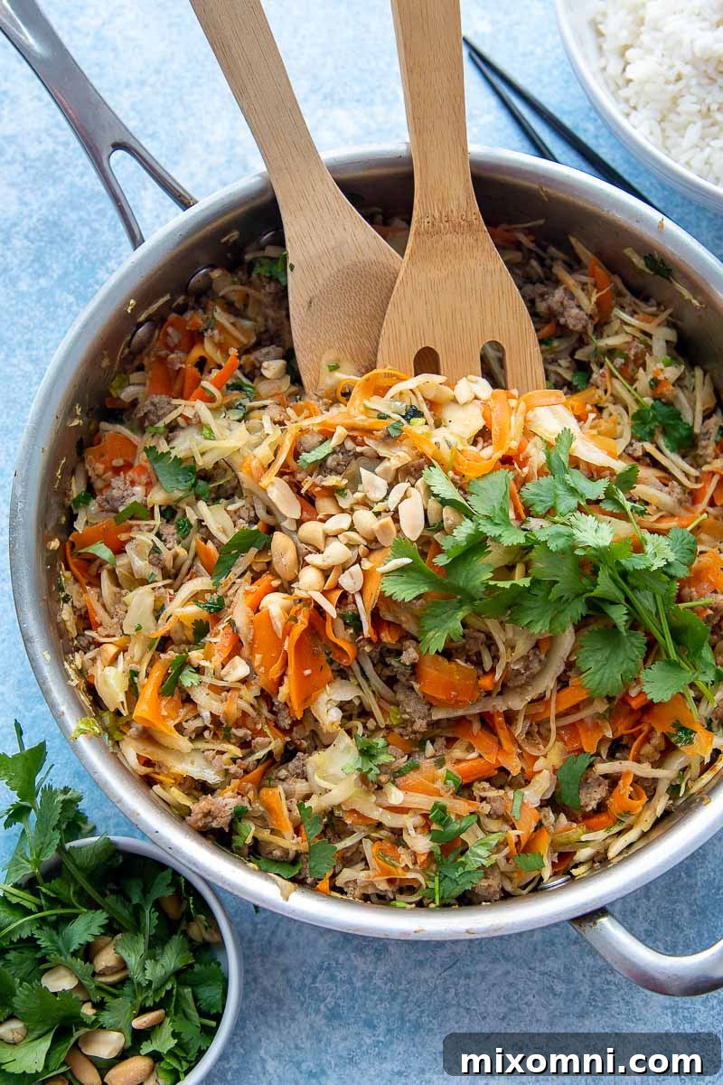 overhead shot of a skillet with egg roll bowl recipe garnished with cilantro and peanuts