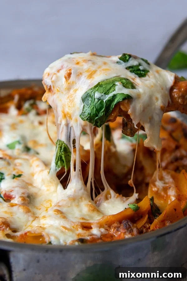 a spatula pulling up a serving of skillet lasagna with cheese dripping down