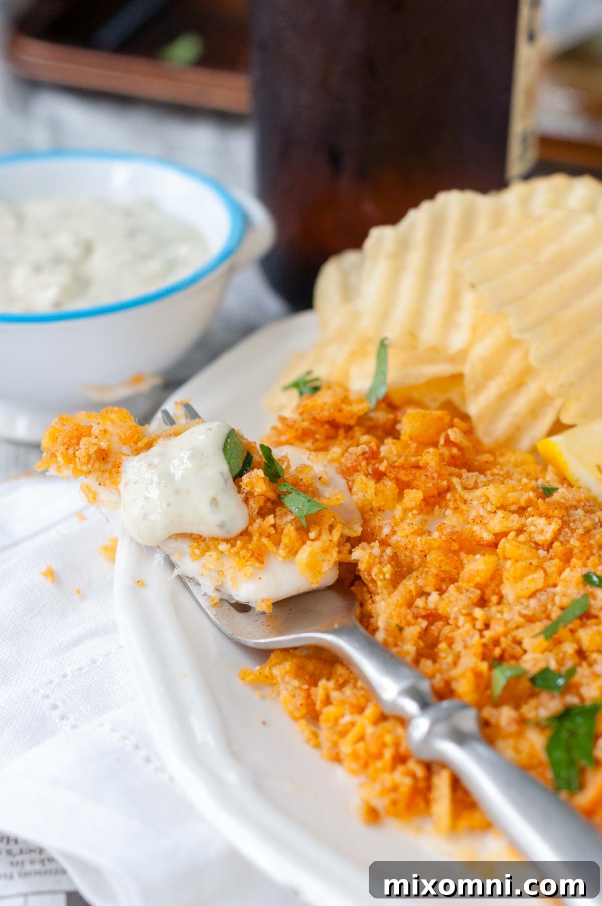 a fork with a bite of fish and tartar sauce on top.