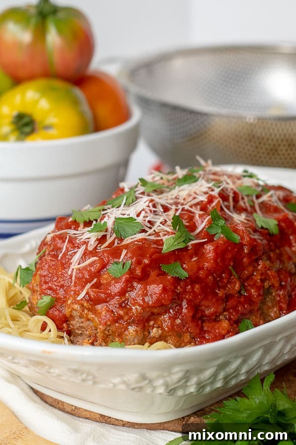 a large white serving dish with Italian meatloaf served on a bed of spaghetti