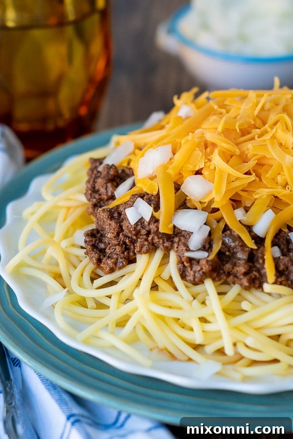 a close up of meat sauce on the pasta with cheese on top and a cup in the background