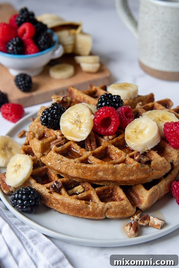 shot of gluten free waffles on a plate with berries, nuts, and bananas on top