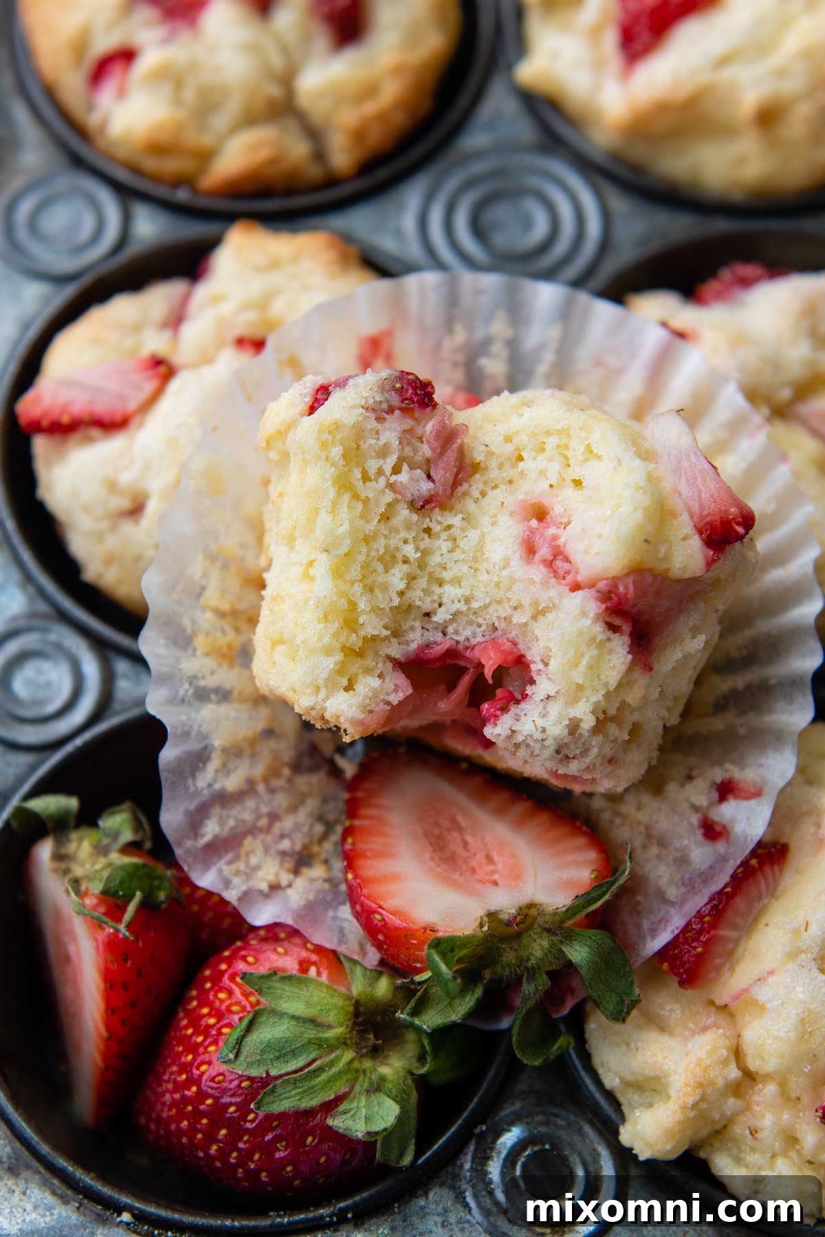 a bitten muffins facing up towards the camera resting on a paper liner.
