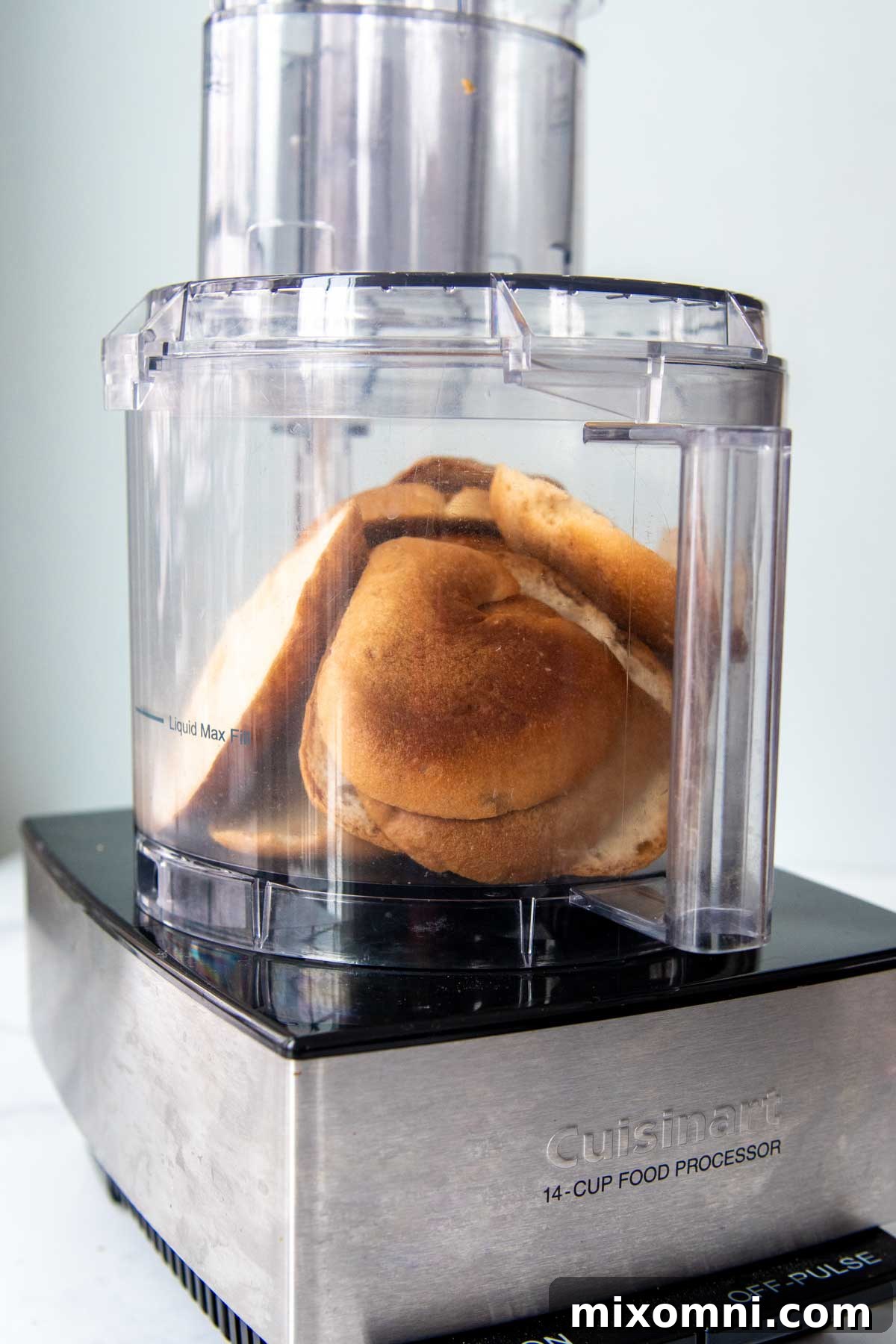 Whole slices of gluten-free bread arranged in a food processor bowl, ready to be processed into crumbs.