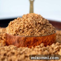 A heaping scoop of golden homemade gluten-free breadcrumbs in a copper measuring cup.