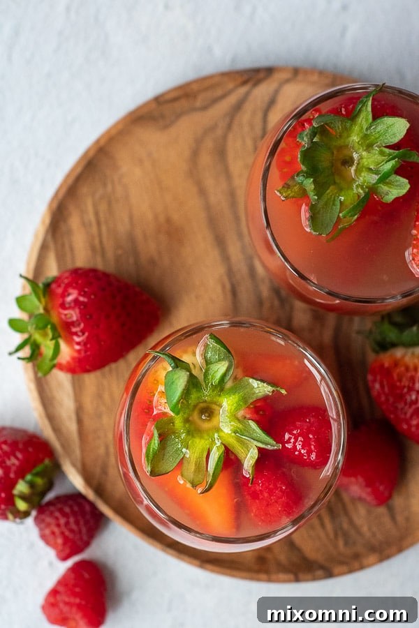 Overhead shot of two glasses of summer berry sangria, garnished with fresh strawberries and raspberries, invitingly displayed.
