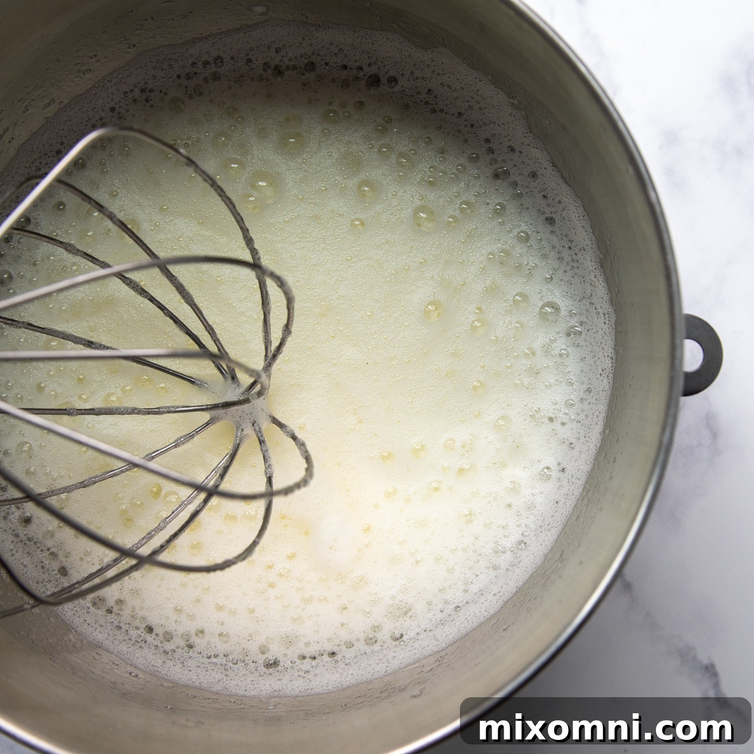Egg whites beaten into a foamy consistency in a mixing bowl.