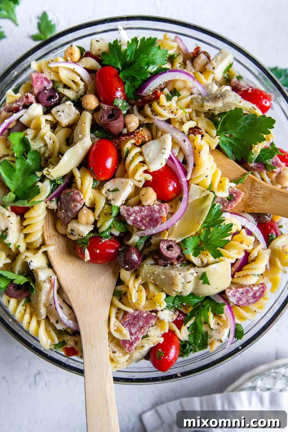 Overhead shot of a vibrant gluten-free pasta salad in a clear glass bowl, showcasing colorful ingredients.