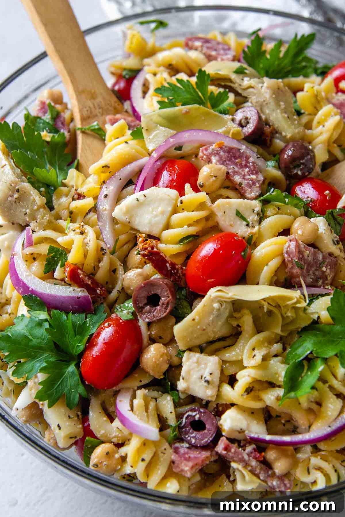 A close-up view of the vibrant gluten-free pasta salad in a clear glass bowl, showcasing the rich colors and textures of the ingredients.