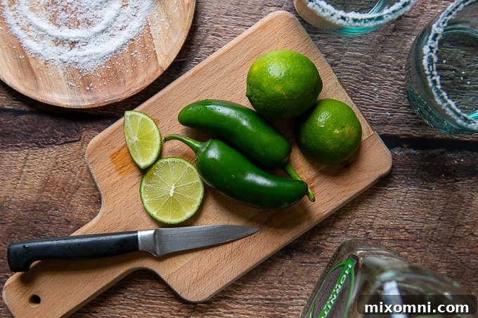 All the essential ingredients for making a delicious spicy jalapeño margarita laid out on a clean surface.