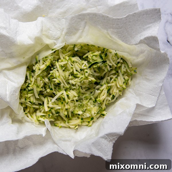 Grated zucchini gently blotted with paper towels to remove excess moisture, a crucial step for perfectly moist gluten-free zucchini bread.