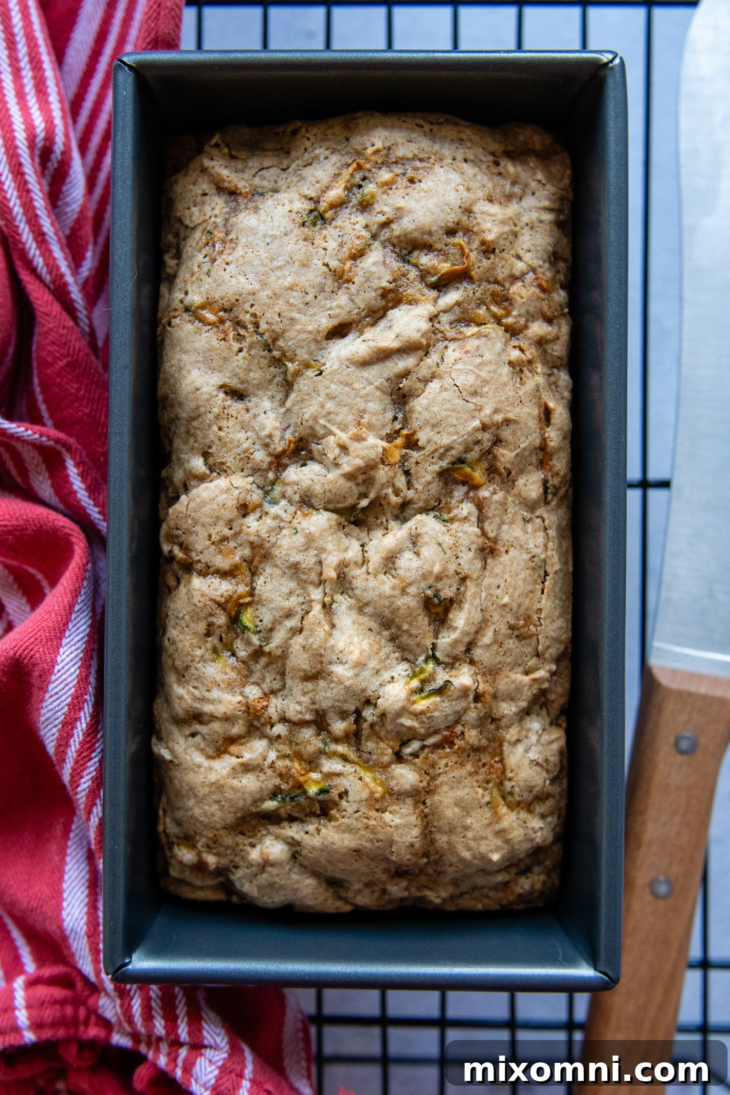 A freshly baked gluten-free zucchini bread loaf cooling in its pan on a wire rack, steam gently rising, promising a perfect texture.