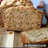 A slice of zucchini bread facing straight on a wooden cutting board.