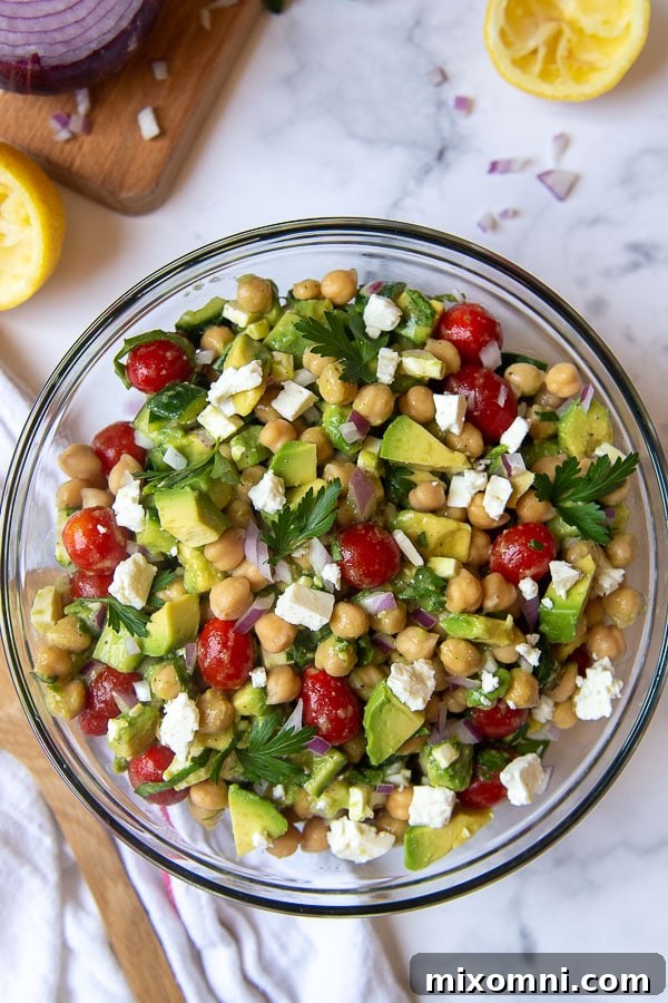 Overhead shot of a colorful Mediterranean chickpea salad with tomatoes, cucumbers, and avocado in a large bowl.