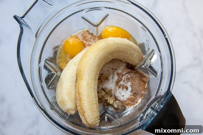 Overhead view of all ingredients for flourless waffles being added to a blender for easy mixing.