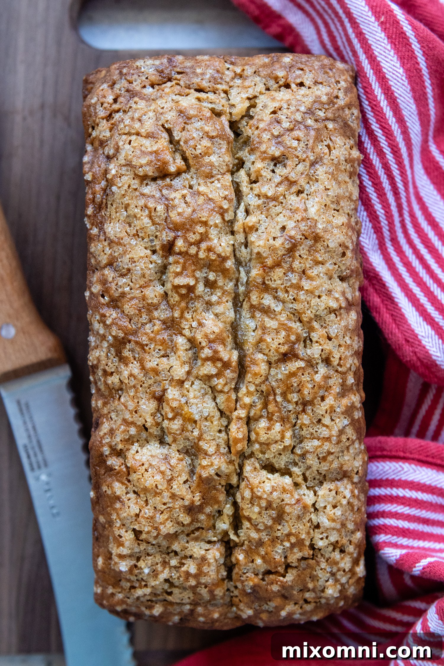 An inviting overhead shot of a freshly baked, unsliced gluten-free banana bread loaf, golden brown and perfectly risen, resting on a wire cooling rack.