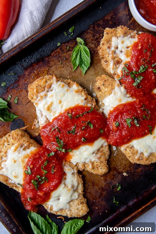 overhead shot of a baking sheet of gluten free chicken parmesan with fresh basil scattered around
