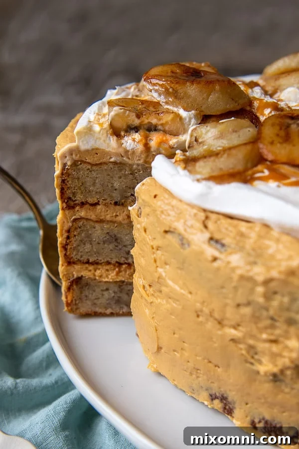 A slice of the decadent banoffee layer cake being carefully pulled out, revealing the multiple layers of banana cake and dulce de leche frosting.