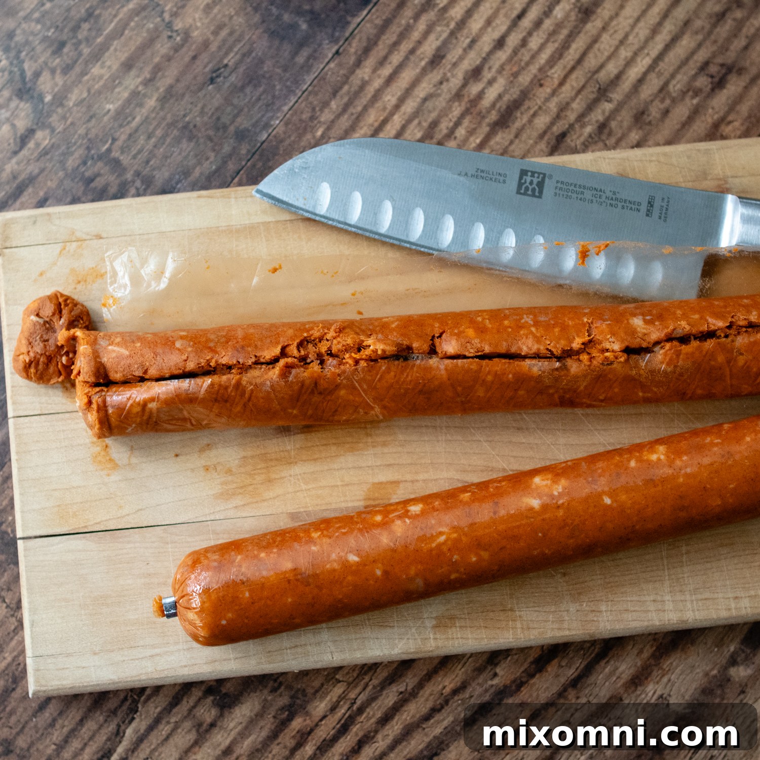 A hand cutting open chorizo casings with a knife, preparing the sausage for cooking.