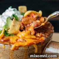 A bowl of chorizo chicken chili with a spoon pulling out a bite