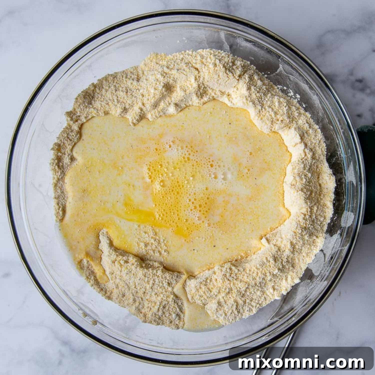 the liquid ingredients being stirred into the dry corn muffin mixture.