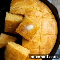 overhead shot of iron skillet with cut cornbread and piece of melting butter on top