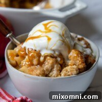 A bowl of gluten-free apple crisp with ice cream and caramel on top, ready to be enjoyed.