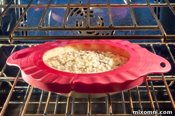 shot of pie baking in oven with pie shield covering crust