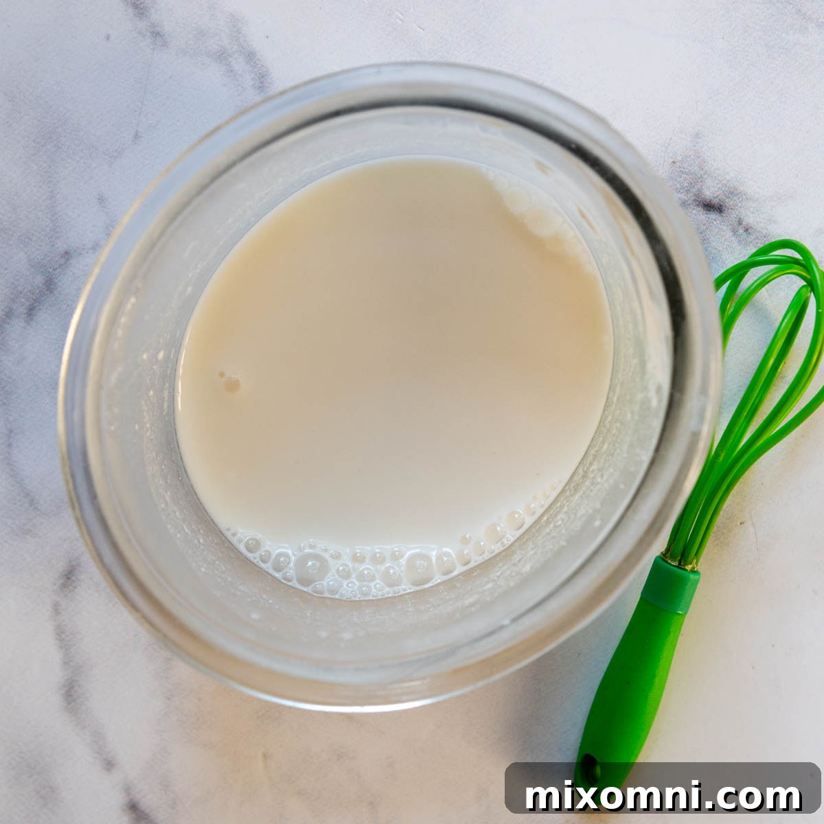 liquid ingredients in a small glass bowl with a whisk next to it.